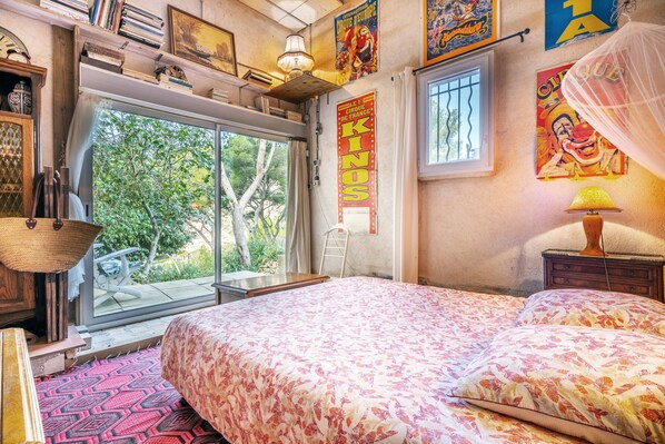 Une chambre avec un grand lit, une fenêtre, une échelle et une affiche accrochée au mur.