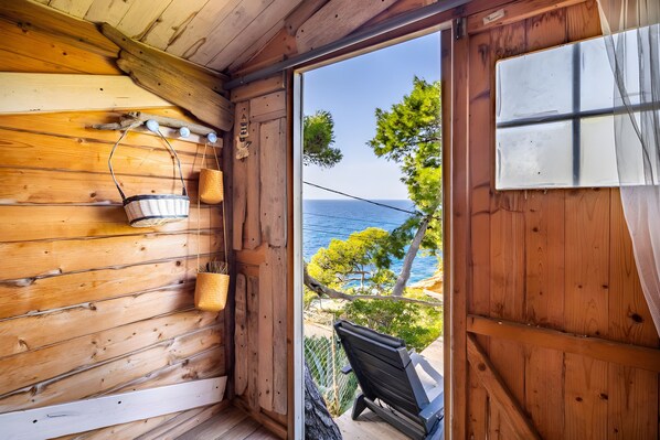 A wooden cabin interior with a view of the sea, a wooden bench, and a hanging basket. - Holiday Home 'Villa Calanques' with Sea View, Private Terrace and Wi-Fi (Ensuès-la-Redonne)