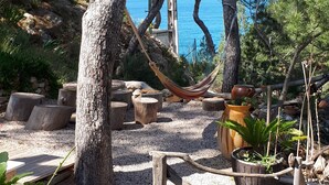 A garden with trees, a hammock, wooden benches, and potted plants. - Holiday Home 'Villa Calanques' with Sea View, Private Terrace and Wi-Fi (Ensuès-la-Redonne)