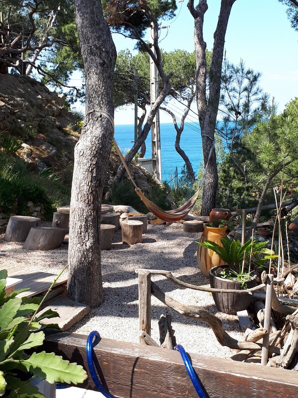 A garden with trees, a hammock, wooden benches, and potted plants. - Holiday Home 'Villa Calanques' with Sea View, Private Terrace and Wi-Fi (Ensuès-la-Redonne)