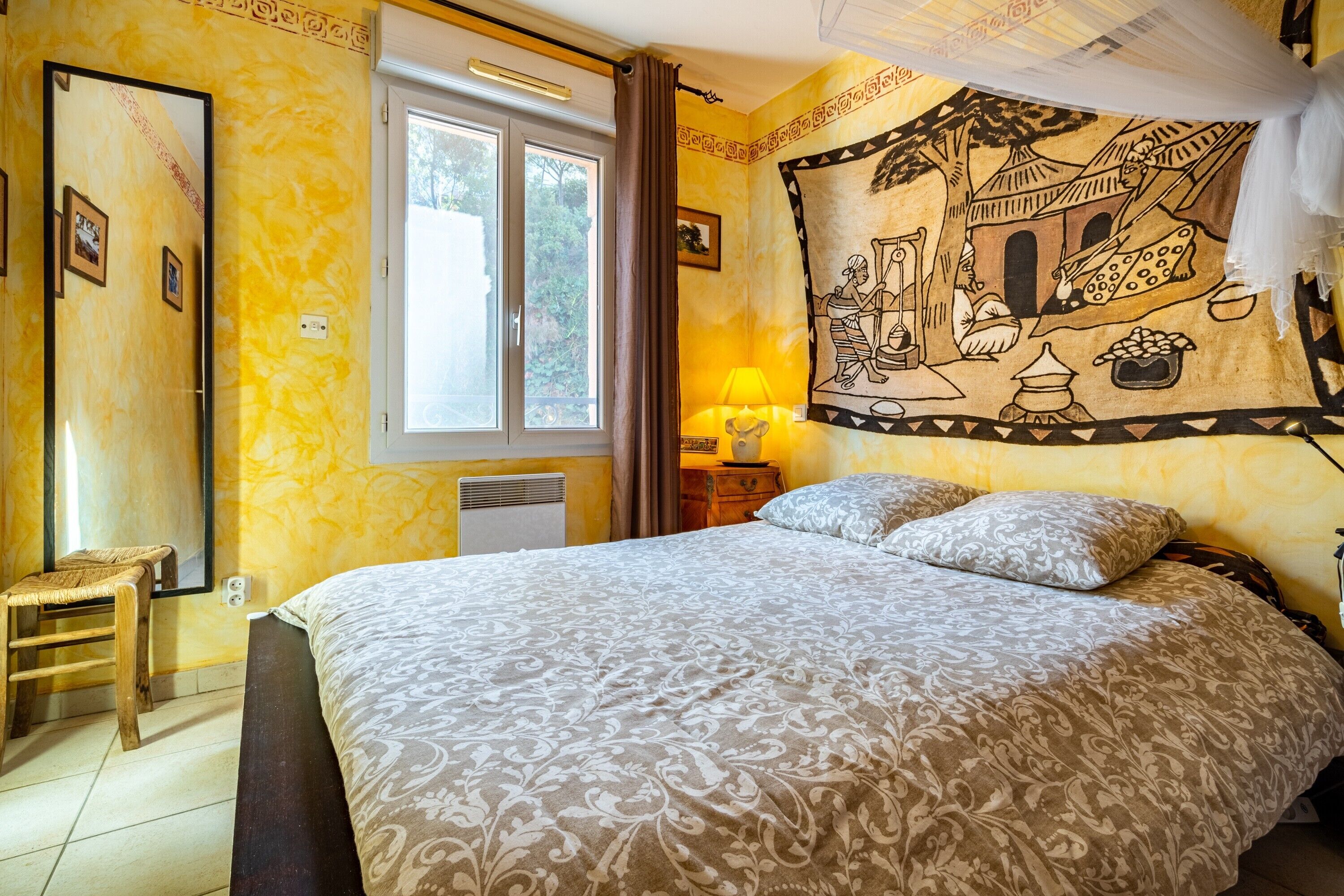 Una camera da letto con un letto, una finestra, un arazzo a parete e una lampada da comodino.
