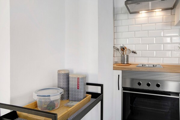 Una cocina con salpicadero de azulejos blancos, horno de acero inoxidable y encimera de madera.