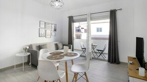 Un salon moderne comprenant un canapé, une table à manger, des chaises, un téléviseur et un balcon avec vue.