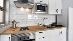 Une cuisine moderne avec des armoires blanches, une cuisinière en acier inoxydable, un four à micro-ondes et un four encastré.