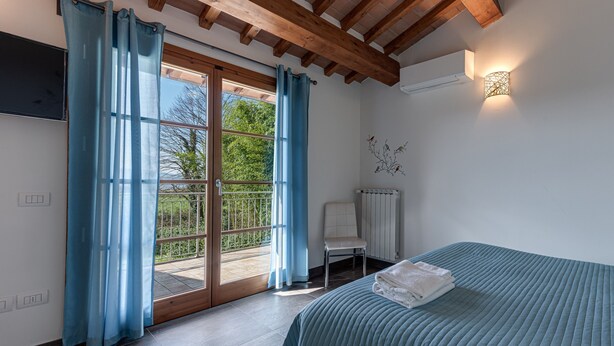 Une chambre à coucher comprenant un lit, une chaise, une fenêtre avec des rideaux, un radiateur et un luminaire fixé au mur.