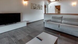 Un salon moderne avec un téléviseur à écran plat, un canapé gris et une table basse.