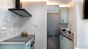 Una cocina compacta con un refrigerador de acero inoxidable, un microondas y un lavamanos.