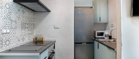 A compact kitchen with a stainless steel refrigerator, a microwave, and a sink.