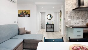 Una sala moderna con un sofá modular, una mesa de comedor y una zona de cocina con salpicadero estampado y una estufa.
