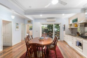Enjoy meals in this dining area with a large table and comfortable chairs, adjacent to a modern kitchen and sliding glass door leading to an outdoor patio.