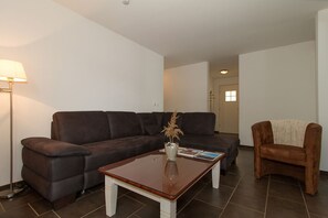 A living room with a dark brown sofa, a wooden coffee table, a brown armchair, and a floor lamp.
