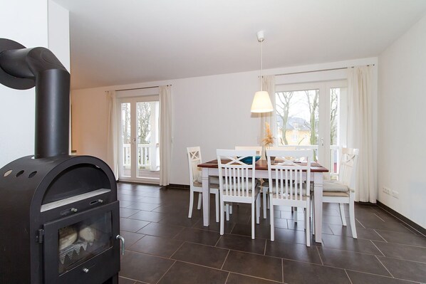 A modern kitchen with a black stove, white chairs, and a dining table.