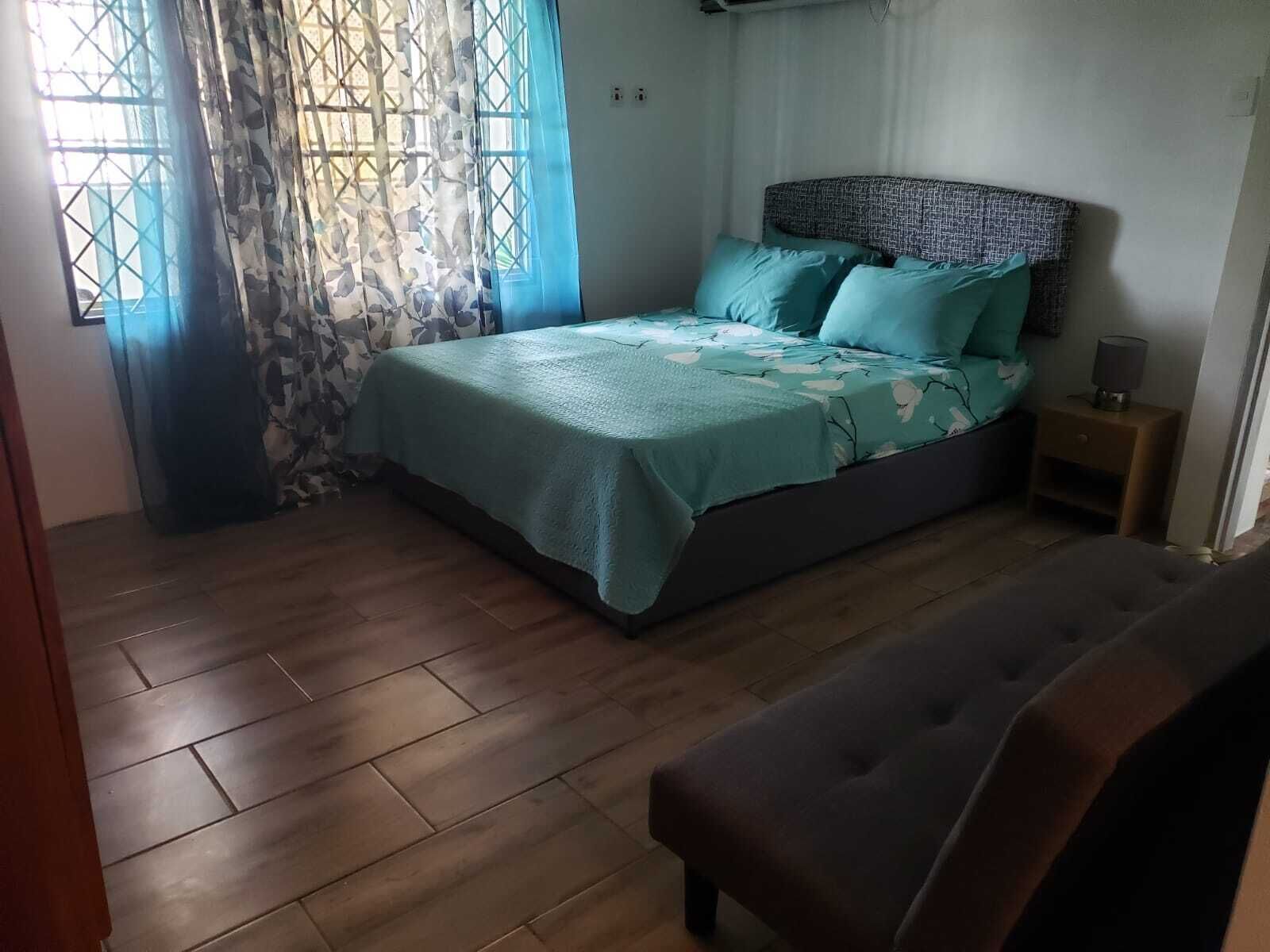 Un dormitorio con una cama, una mesita de noche y un banco.