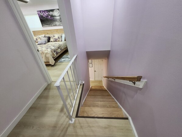 A narrow staircase with a wooden handrail and a white wall on one side.