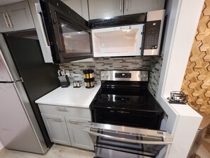 A compact kitchen with a black refrigerator, a microwave, a stove, and a built-in oven.