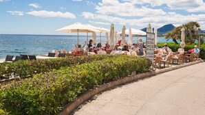 A seaside restaurant with outdoor seating, a view of the sea, and a mountain in the background. - Can Christin - central with pool (Cala Ratjada)