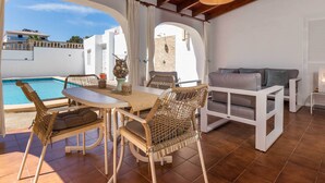 A sunlit patio with a pool, wicker furniture, and a white sofa. - Can Christin - central with pool (Cala Ratjada)