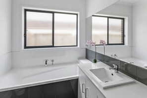 A modern bathroom with two sinks, a large mirror, and frosted windows.