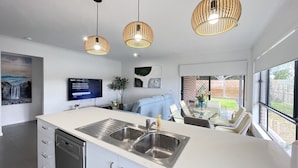 Een moderne keuken met een groot eiland, een roestvrijstalen spoelbak en hangende lampen.