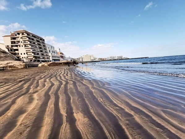 Una playa arenosa con un edificio a la izquierda.