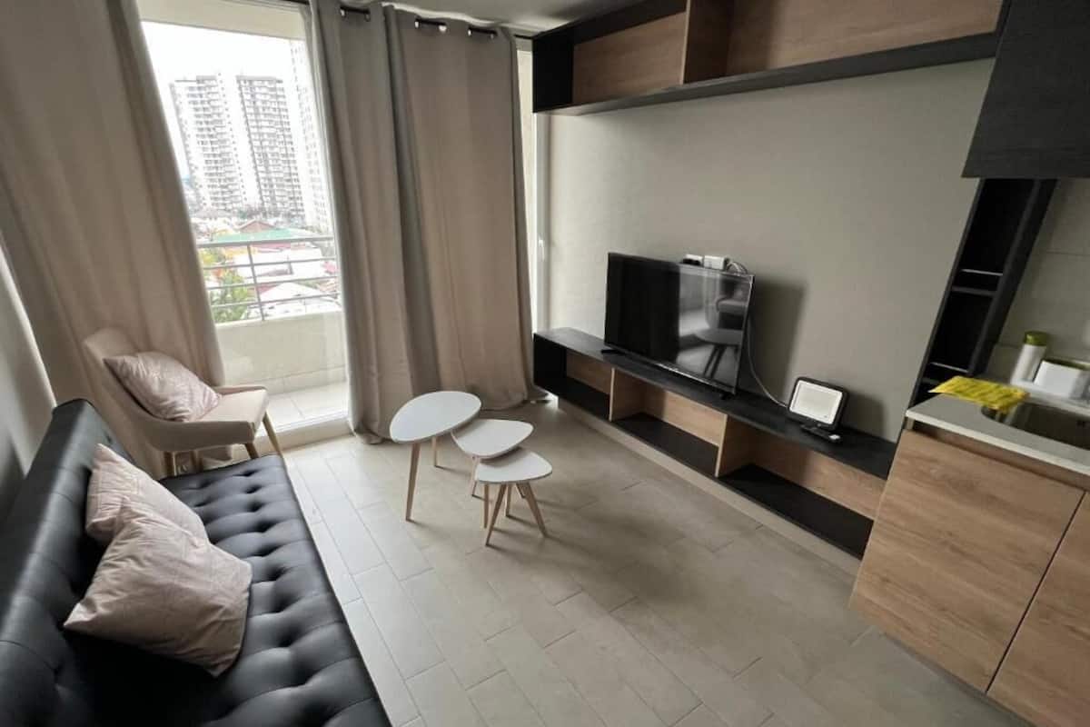 A modern living room with a sofa, a TV, a small table, and a chair.