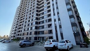 Un edificio de gran altura con varios balcones y un estacionamiento al frente.