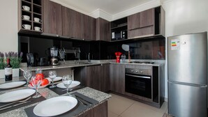 Una cocina moderna con armarios de madera oscura, un refrigerador de acero inoxidable y una encimera de granito.