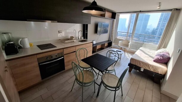 Una cocina moderna con comedor, un balcón pequeño y una cama.