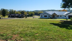 A residential area with houses, a grassy field, and a clear sky. - Great House, Great Vibe. Lake Access/View, Clean, Quiet, Family Pet Friendly. (Sevierville)