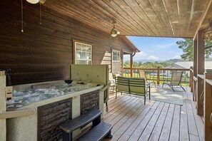 Une terrasse en bois avec un jacuzzi, un espace salon extérieur et une vue sur le paysage.