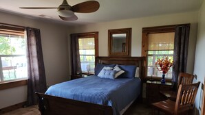 A bedroom with a large bed, wooden headboard, a ceiling fan, and two windows with curtains. - Great House, Great Vibe. Lake Access/View, Clean, Quiet, Family Pet Friendly. (Sevierville)