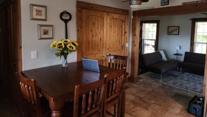 A dining area with a wooden table, chairs, a laptop, and a vase of sunflowers. - Great House, Great Vibe. Lake Access/View, Clean, Quiet, Family Pet Friendly. (Sevierville)