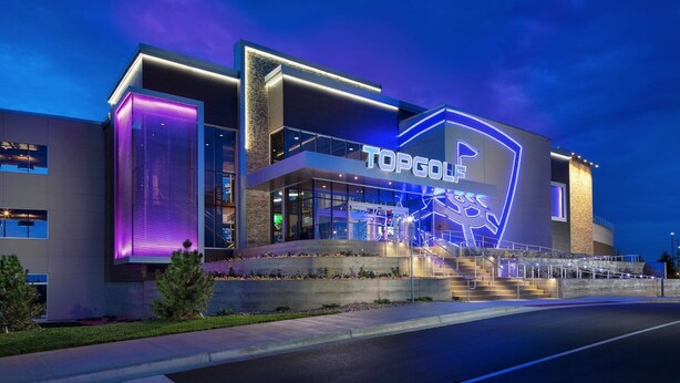 A modern TopGolf facility with a prominent illuminated sign, a well-lit entrance, and a landscaped area with steps leading up to the building. - Luxury Remodel in Phoenix ~ EV Charger, Putting Green, Family & Pet-Friendly (Phoenix)