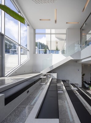 Un interior moderno con ventanas amplias, una escalera y una zona de estar.