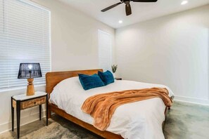 Une chambre à coucher avec un lit, une table de chevet, une lampe et un ventilateur de plafond.