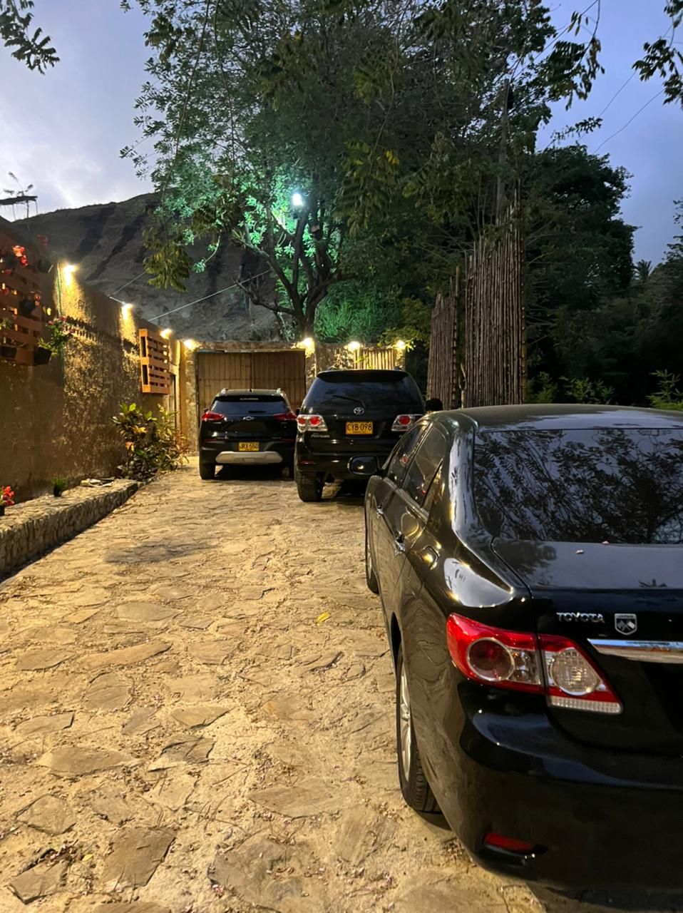 A paved driveway with parked cars and a building with a sloped roof.