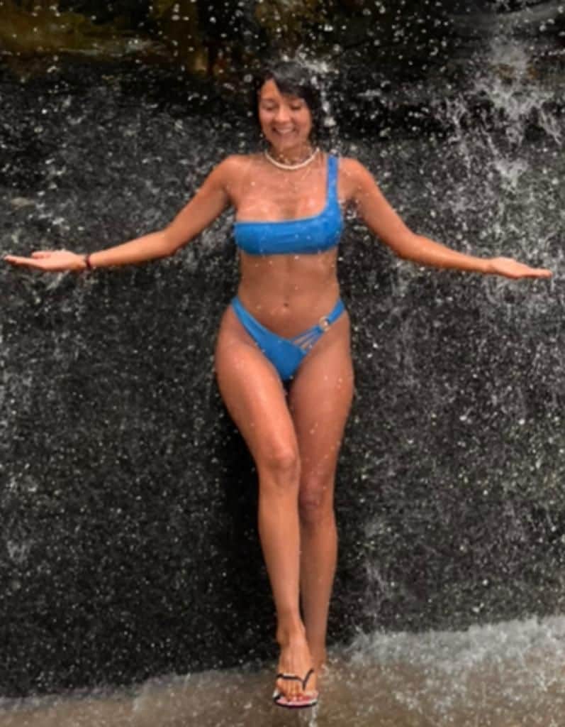 Una persona con traje de baño azul de pie frente a una cascada.