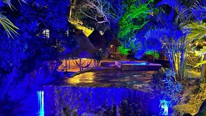 A tropical garden with a thatched-roof hut, a small pool, and lush greenery. - TAWACA ECOHOTEL (Santa Marta)