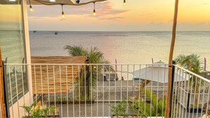 A balcony with a wooden table and chairs, overlooking the sea with boats in the distance. - Resort Queen Sea (Phu Quy)