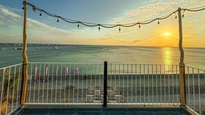 A balcony with a metal railing, a view of the sea, and a sunset. - Resort Queen Sea (Phu Quy)