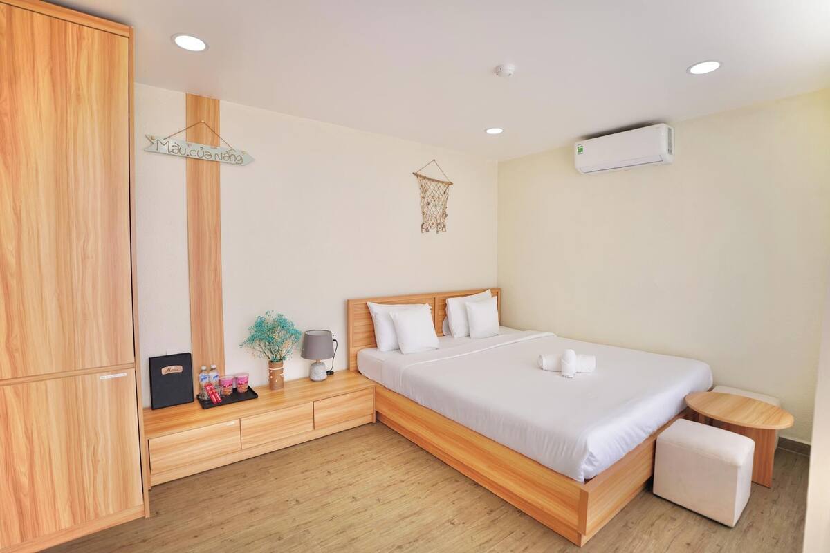 A bedroom with a wooden bed frame, a bedside table, a small round table, and a wardrobe.