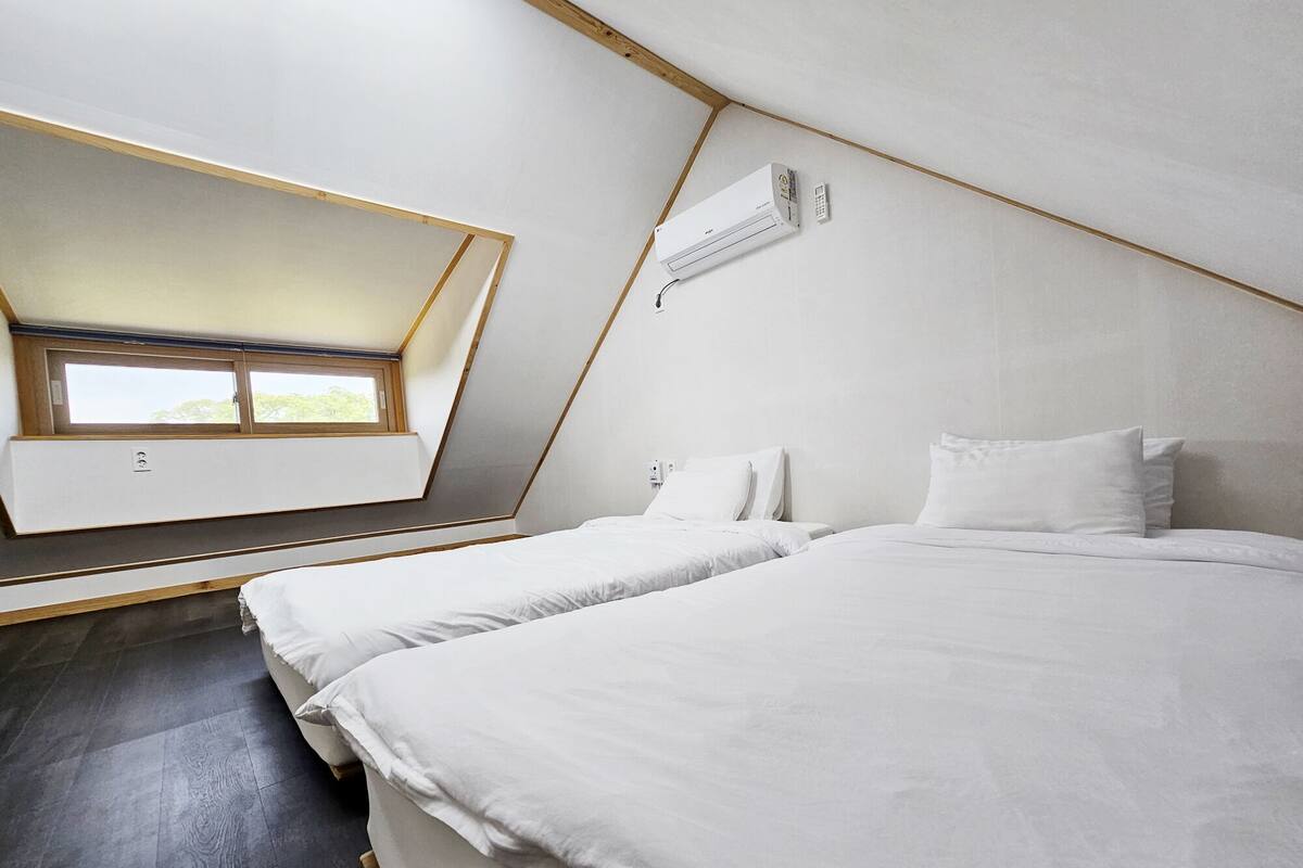 A bedroom with two beds, a skylight, and an air conditioning unit.