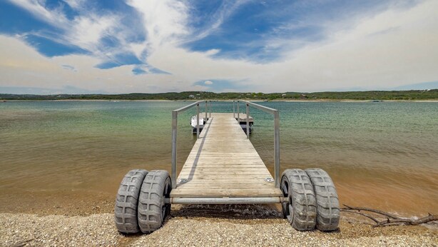 A wooden pier extending into a calm body of water with a clear sky above. - Billie Jean, Lake Travis - Sleeps 8 Lake Access (Point Venture)