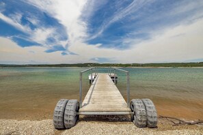 A wooden pier extending into a calm body of water with a clear sky above.