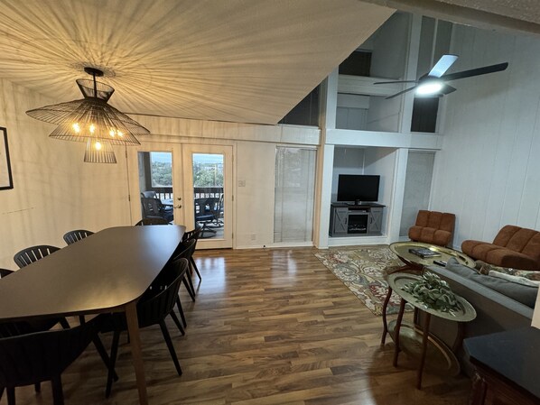 A spacious living area with a dining table, sofas, and a TV.