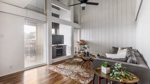 A spacious living room with a large TV, a sofa, a coffee table, and a fireplace. - Billie Jean, Lake Travis - Sleeps 8 Lake Access (Point Venture)