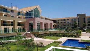 A modern hotel with multiple floors, a central courtyard with a swimming pool, and a staircase leading to the upper levels.