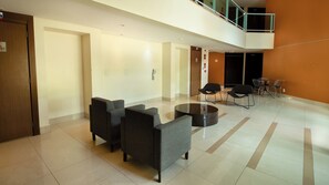 A lobby with a reception desk, a seating area with sofas and chairs, a small table, and a staircase leading to an upper level. - The Sun Resort - Super Apartamento de 2 Quartos (Brasília)