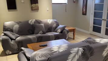 Un salon avec un canapé gris, une table basse en bois et une petite table d’appoint.