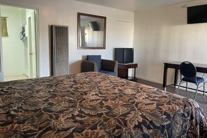 A hotel room with a large bed, a desk with a chair, a television, and a wardrobe. - Oak Motel Modesto CA (Modesto)